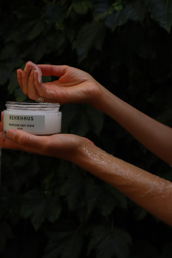 Hands holding a jar of magnesium chloride body scrub 