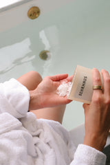 WOMAN ADDING MAGNESIUM BATH SOAK TO BATH