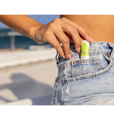 Person placing Raw Elements SPF 30 Lip Rescue into denim pocket outdoors