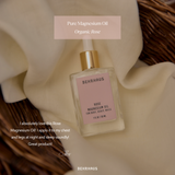 Behrhaus Rose Magnesium Oil in a glass dropper bottle on soft fabric with organic rose scent, used for relaxation, sleep, and body care.