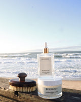 retreat gift set which is magnesium oil, magnesium body scrub and dry brush sitting on the dock in front of the ocean 